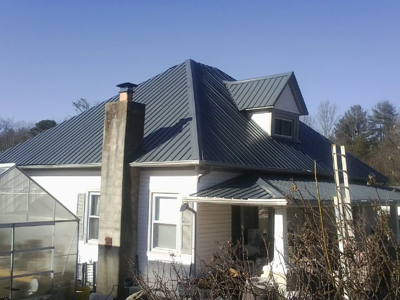 Dark blue standing seam metal roof on a white farmhouse with dormer — Slate & Tile Roof Repair by Roofing Brothers in North Branford