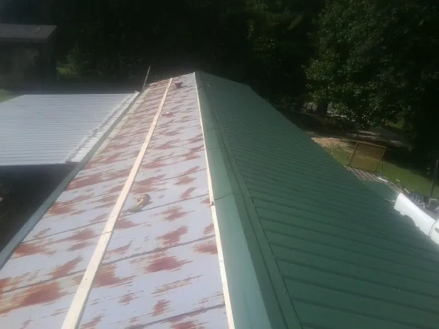 Old rusted panels beside newly installed green metal roofing — Wind Damage Roof Repair by Roofing Brothers in North Branford