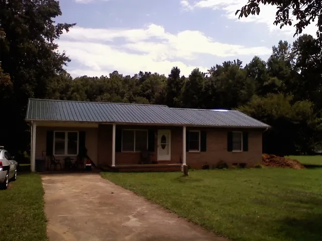 Dark green metal roof on a brick ranch with a covered porch in North Branford