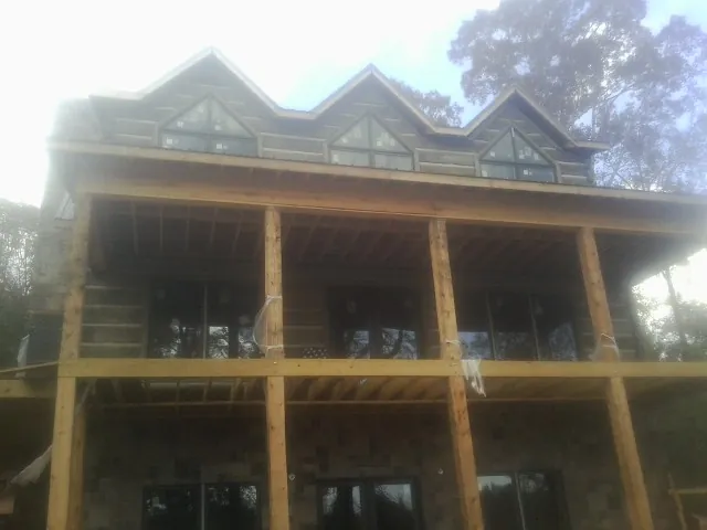 Dormers and porch framing on a large log home under construction — Roof Coating work by our crew in North Branford