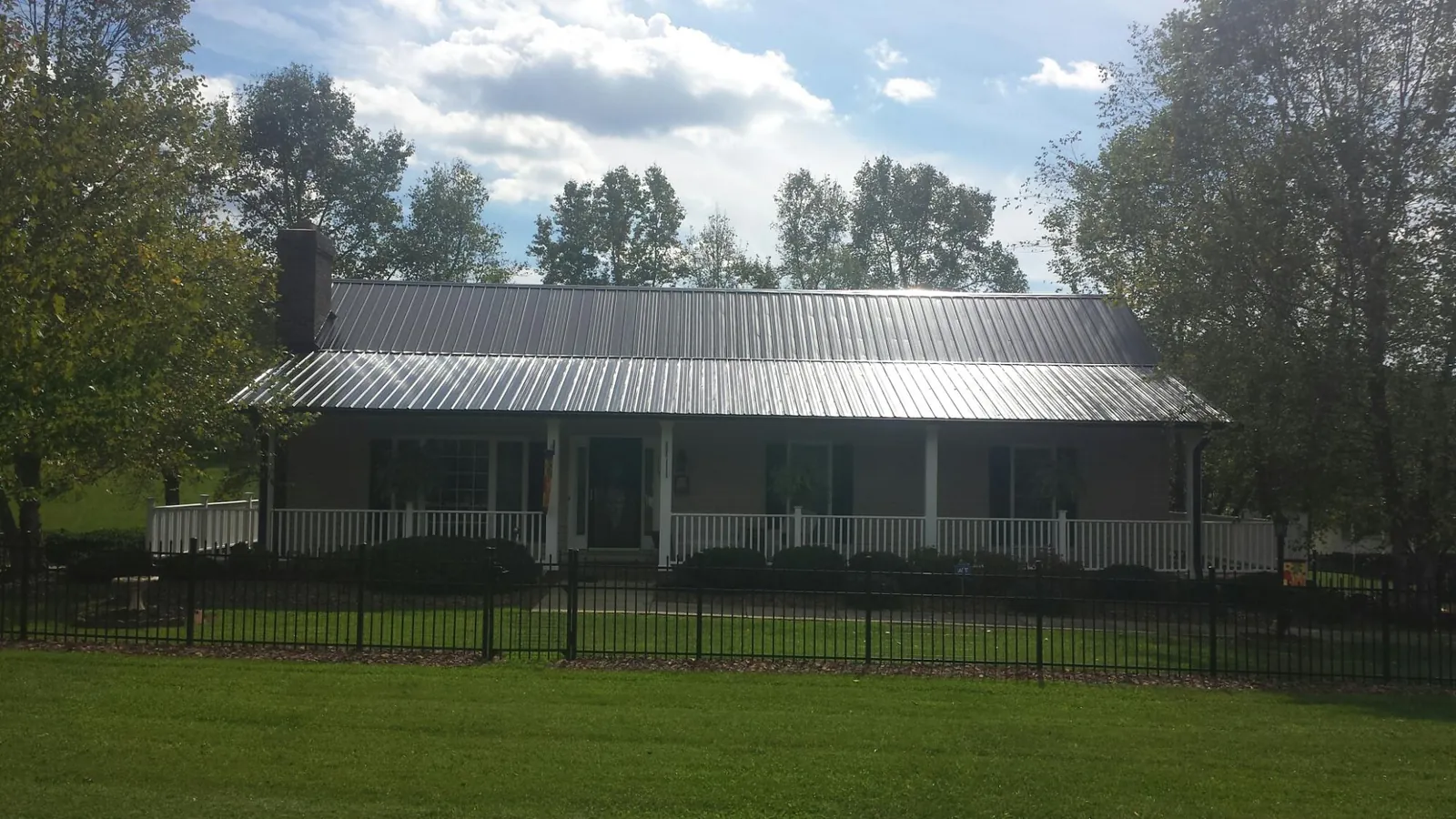 Gray metal roof on a brick ranch with a full width front porch — Gutter Guard Installation work by our crew in North Branford