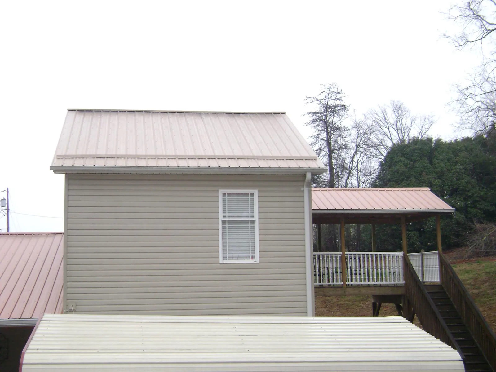 Tan metal roofs on a two story addition and attached porch, from a Roof Replacement job in North Branford