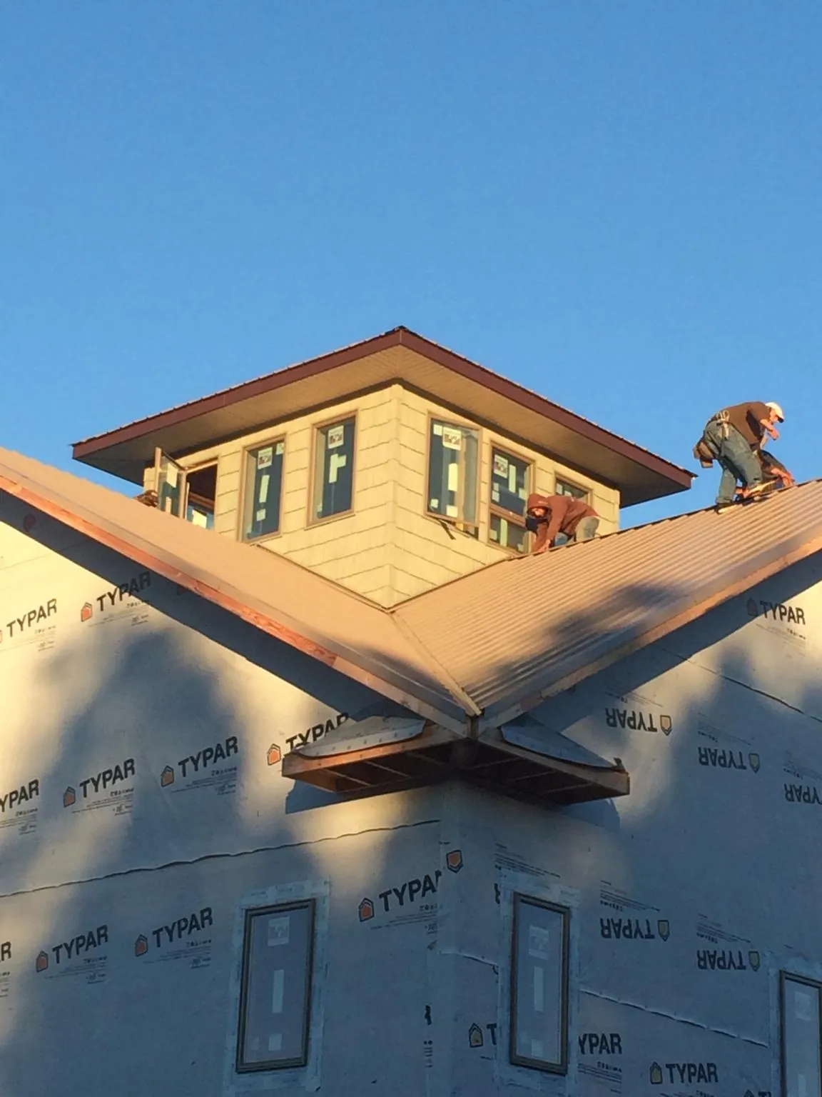 Roofers working around a rooftop cupola on a new metal roof at sunset — Roof Waterproofing in North Branford by Roofing Brothers
